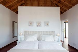 two beds in a bedroom with white walls and wooden ceilings at Villas Taburiente in Los Llanos de Aridane