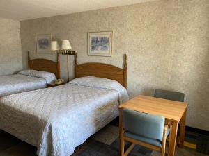Habitación de hotel con 2 camas, mesa y silla en Riverfront Lodge, en Burkesville