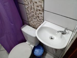 La salle de bains est pourvue de toilettes blanches et d'un lavabo. dans l'établissement Linda kitinet, à Cabo Frio
