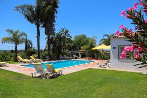 a swimming pool with lawn chairs and palm trees at Idyllic Farm House with huge Garden for 14PAX in Almancil