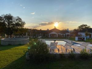 un gruppo di sedie seduti intorno a una piscina con il tramonto di Steenkoppies Estate semi self catering unit 2 a Magaliesburg