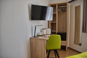 Hotel Garni Ilys Inn في فيلس: غرفة بها مكتب مع كرسي أخضر وتلفزيون