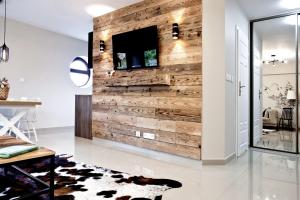 a living room with a wooden wall with a flat screen tv at Aba Apartamenty Piłsudskiego 41 in Krynica Zdrój