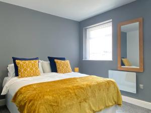 ein Schlafzimmer mit einem großen Bett und einer gelben Decke in der Unterkunft Mayfair Suite Sasco Apartments in Blackpool