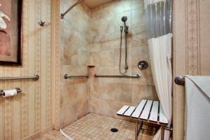 a bathroom with a shower with a bench in it at The Inn at Charles Town / Hollywood Casino in Charles Town