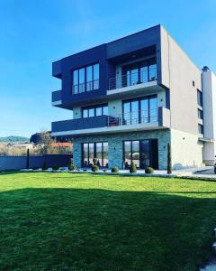 une maison avec une pelouse devant elle dans l'établissement Papa Apartments, à Berovo