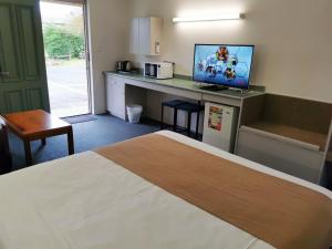 Habitación de hotel con cama y escritorio con TV. en Ballarat Eureka Lodge Motel, en Ballarat