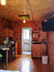 cocina con armarios de madera y TV en una habitación en Cabaña Mountain View, en Heredia