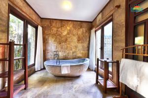 ein Bad mit einer großen Badewanne in einem Zimmer mit Fenstern in der Unterkunft Sun Spa Resort & Villa in Dong Hoi