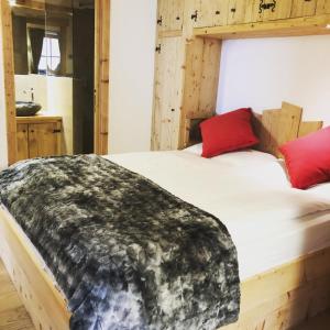 um quarto com uma cama de madeira e almofadas vermelhas em Ciasa Coletin em Alvera