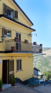 ein gelbes Haus mit einem Balkon und einer Bank in der Unterkunft Casa Santa Rita / Locazione turistica Sicilia / Santa Domenica Vittoria in Santa Domenica Vittoria