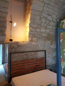 een bed in een kamer met een stenen muur bij Casa Santa Maria - Fichi d'india in Ragusa