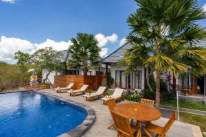 珀尼达岛WK Gamat Garden的房屋旁的游泳池配有桌椅