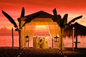 a tent on the beach with a sunset in the background at Anse Chastanet Resort in Soufrière