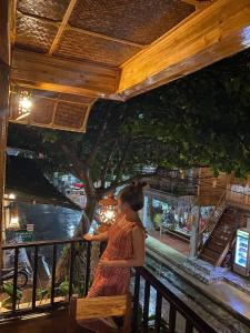 a woman sitting on a bench looking at a river at Mai Chau Green Ecohouse in Hòa Bình