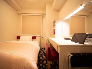 a room with two beds and a desk with a computer at Hotel Front Inn Fukuoka Airport in Fukuoka