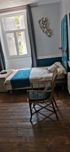 a bedroom with a bed and a chair next to a window at Charmant Studio au calme à 5 min du centre ville in Saint-Claude