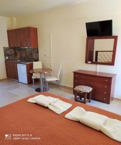 a room with a bed with a table and a kitchen at Toula's Apartments in Sidari