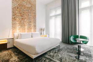 a bedroom with a white bed and a green chair at Hotel C2 in Marseille