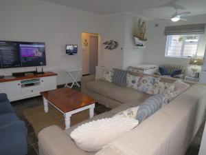 a living room with a couch and a tv at Seagulls Beach House in Port Shepstone