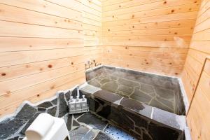 a bathroom with a tub in a wooden wall at YUFU-Inn プライベートな露天風呂付き-由布院駅徒歩2分-最大8名宿泊可能 in Yufuin