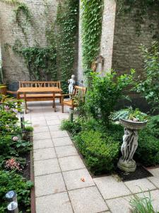 a patio with two benches and a birdbath in a garden at Hotel Gunia in Berlin