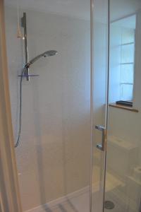 a shower with a glass door in a bathroom at Plain Street Cottage, The Barn B&B in Port Isaac