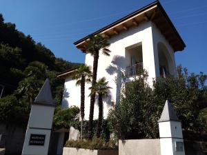 un edificio blanco con palmeras delante en Marenca Residence en Cannobio