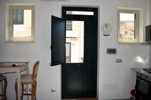 ノートにあるCasa Vacanze "A Machina Ro Ghiaccio"の黒いドア付きのキッチン(壁掛け時計付)