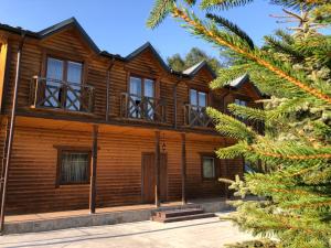 a wooden house with windows and a pine tree at Брусний View House in Sheshory +38 photos
