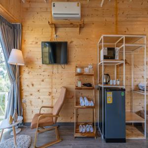 a room with a wooden wall with a refrigerator and a tv at แคมป์ต๊ะต่อนยอน แม่กำปอง เชียงใหม่ CAMP Ta-Torn-Yorn Maekampong Chiang Mai in Mae On