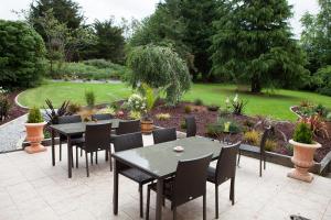 een patio met tafels en stoelen en een tuin bij Hotel Le Branhoc - Brit Hotel Auray in Auray