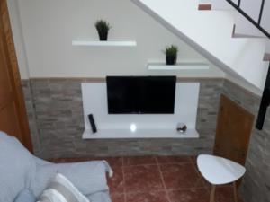 un soggiorno con una TV a schermo piatto su una parete di Casa los abuelos 1 a La Goleta