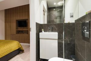 a bathroom with a shower and a sink and a bed at Arcore Premium Apartments The Strand in London