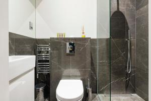 a bathroom with a toilet and a glass shower at Arcore Premium Apartments The Strand in London