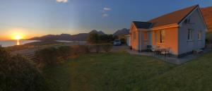 a house with the sunset in the background at SOLACE COTTAGE in Bunaveneadar