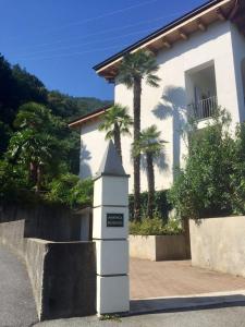 una casa blanca con palmeras delante en Marenca Residence en Cannobio