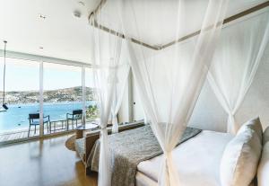 a bedroom with a bed and a view of the ocean at Cape Bodrum Luxury Hotel & Beach in Gundogan