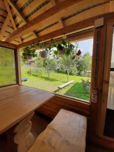 a porch with a wooden table and a large window at Casa Roua Muntilor in Vatra Dornei