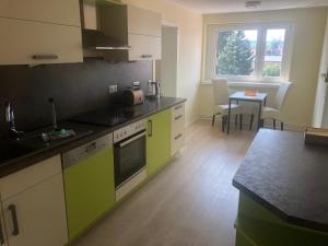 uma cozinha com armários amarelos e verdes e uma mesa em Fahrradpension-Joachimsthal em Joachimsthal
