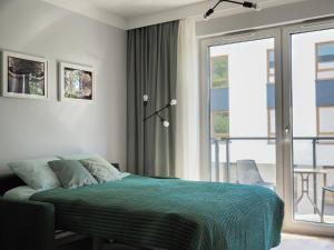 sypialnia z zielonym łóżkiem i balkonem w obiekcie Kropla Rosy we Wrocławiu