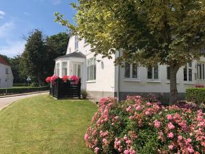 a white house with pink flowers in front of it at Vemmingbundvejens Ferielejlighed in Broager