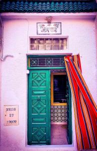 eine grüne Tür an einem Gebäude mit einem Schild darüber in der Unterkunft Dar EL Hamra Maison Typique in Mahdia