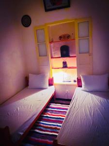 two twin beds in a room with a window at Dar EL Hamra Maison Typique in Mahdia