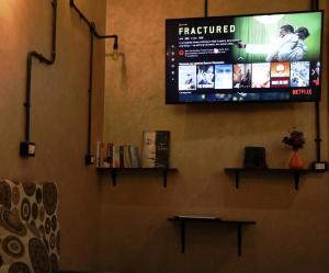 a flat screen tv on a wall with books at Holy Sheet Hostel in Cairo