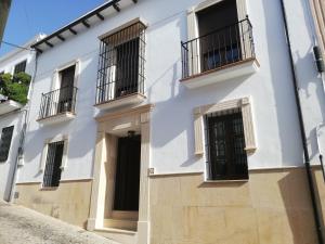 een wit gebouw met zwarte deuren en balkons bij Casa Candela in Ronda