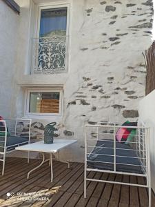 a patio with two chairs and a table and a stone wall at la casita in Le Bourg-dʼOisans