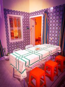 a room with two beds and two red stools at Dar EL Hamra Maison Typique in Mahdia