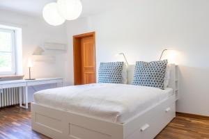 ein weißes Bett mit blauen Kissen im Schlafzimmer in der Unterkunft Im Schneewinkl in Schönau am Königssee