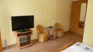 ルチャネ・ニダにあるMazurska Perla Malgorzataのテレビ、椅子2脚、テーブルが備わる客室です。